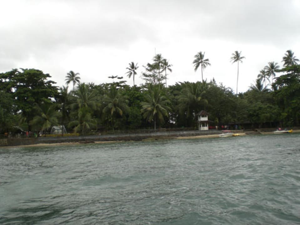 Blick vom Boot auf den schmalen Strandstreifen Mutiara Carita Cottages