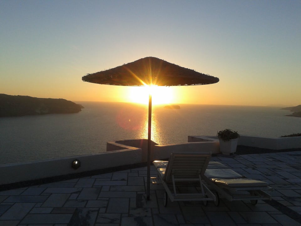 Sonnenuntergang hinter Pool und Liegen Caldera's Dolphin Suites