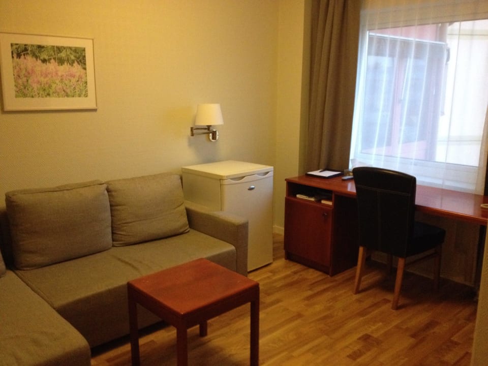 Wohnbereich mit Couch und Kühlschrank sowie Tisch Ta Inn Hotel