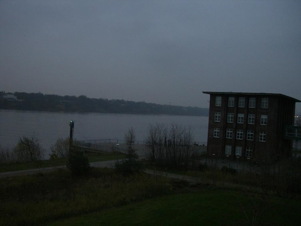 Seitlicher Ausblick auf ein Gebäude und die Elbe  elaya hotel hamburg finkenwerder