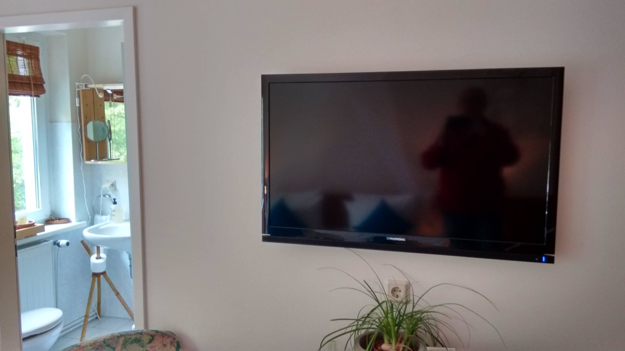 Großer Flachbild TV, links Blick ins kleine Bad Lodge Seaside Boutique Hotel