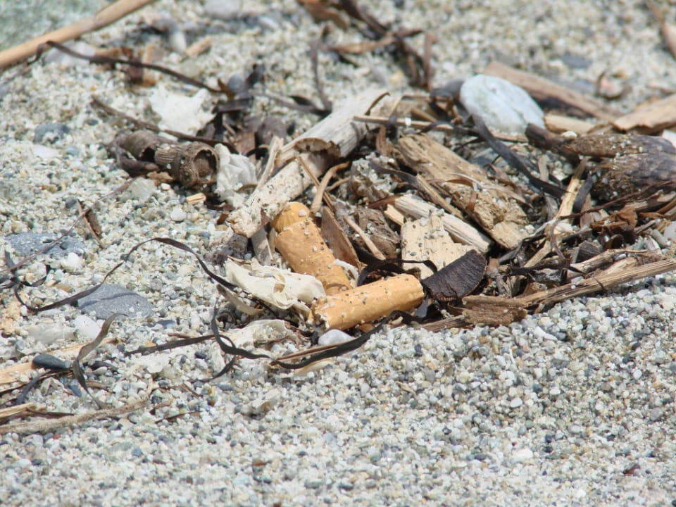 Zigarettenkippen im Sand vom Strand Olympian Bay Grand Resort