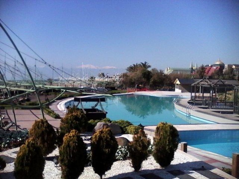 Blick über den Pool zu den schneebedeckten Bergen Limak Lara Deluxe Hotel & Resort