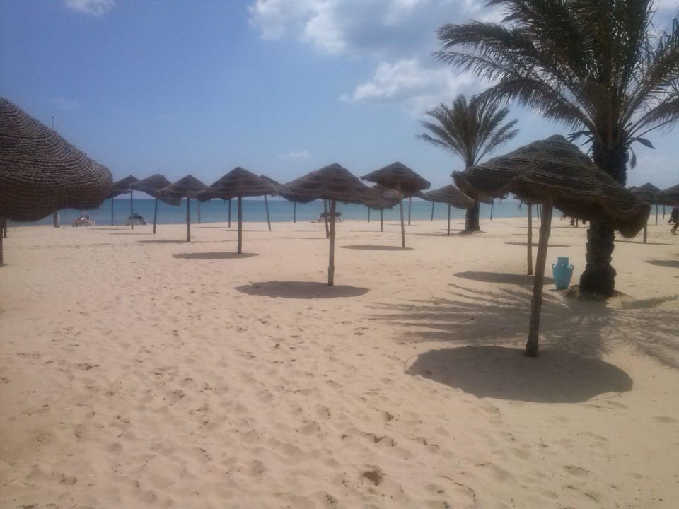 Strand mit den renovierungsbedürftigen Schirmen Hotel Paradis Palace