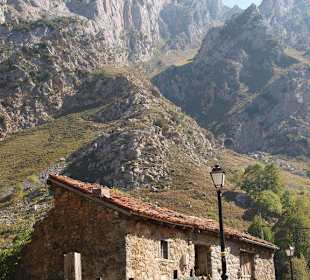 Steinhaus mit steilen Bergen im Hintergrund