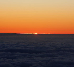 Die Sonne schaut über den Wolken