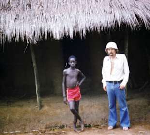 Jerzy mit einem Kind vor einer Savannenhütte