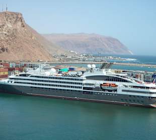 Kreuzfahrtschiff vor Containern
