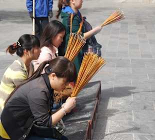 Gläubige mit Räucherstäbchen beim Gebet