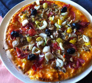 Hauspizza aus dem Holzofen