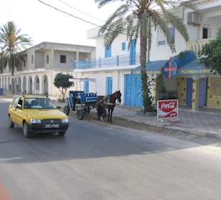 Straße vorm Hotel mit Kutsche und Taxi