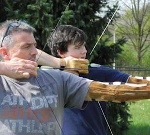 Vater und Sohn beim Bogenschießen im Freizeitpark-