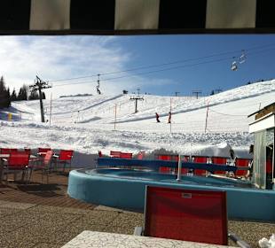 Terrasse mit Sonne, Skifahrer und Liftstation