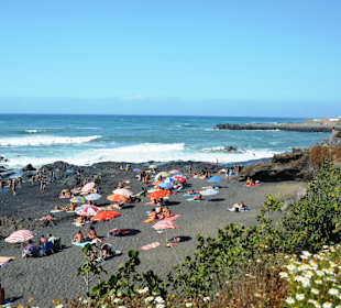 Schwarzer Strand mit viel Grün