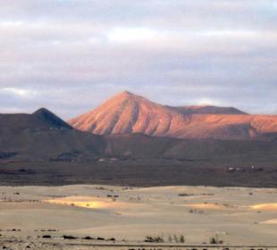 Dünenlandschaft und Berge im Abendlicht