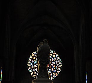 Madonnenstatue mit Fensterrose im Hintergrund