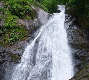 Baden im Wasserfall mit einem Abenteurer darüber