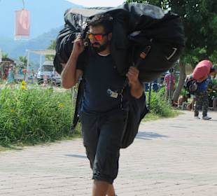 Paragliderpilot schleppt das Equiptment zum Bus