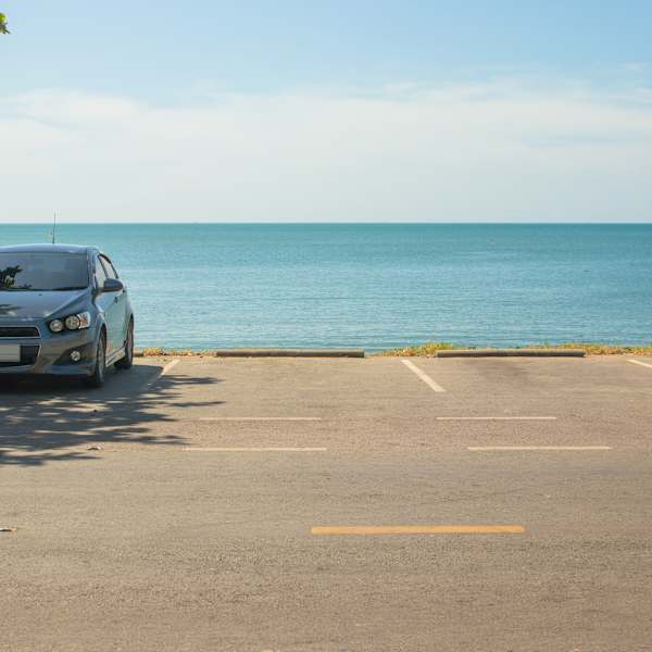 Ein Auto steht einsam an einem Parkplatz. Dahinter liegt das Meer.