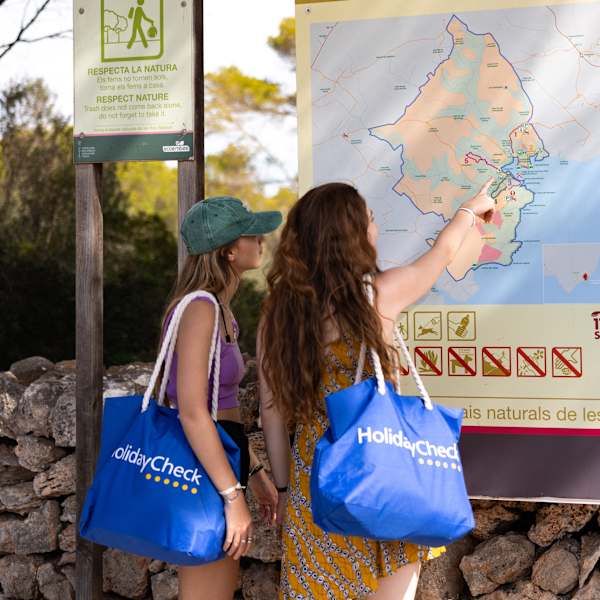 Zwei Frauen stehen vor einem Lageplan am Strand und verschaffen sich einen Überblick © HolidayCheck