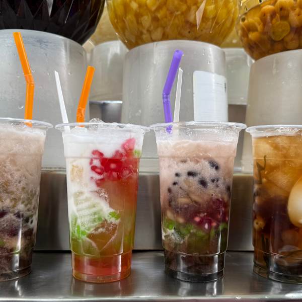 Vier durchsichtige Becher mit bunten Flüssigkeiten und Desserts.