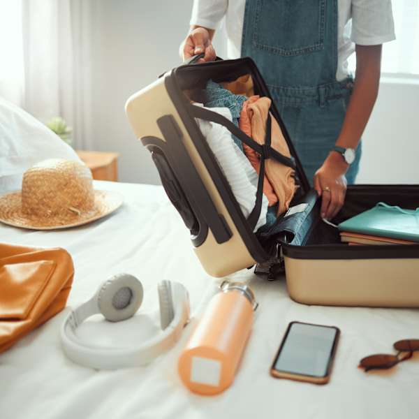 Eine Person packt einen Koffer auf dem Bett.