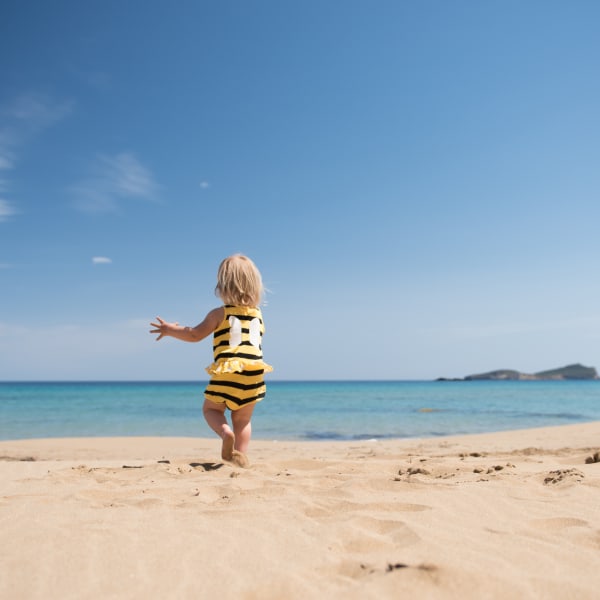 Kleines Mädchen rennt glücklich über einen Sandstrand im Urlaub © iStock.com/kamsta