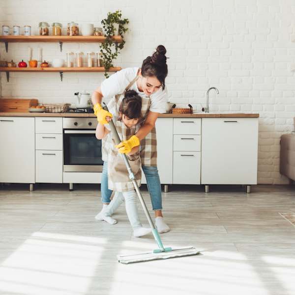 Eine Frau und ihre kleine Tochter putzen gemeinsam in ihrem Zuhause.