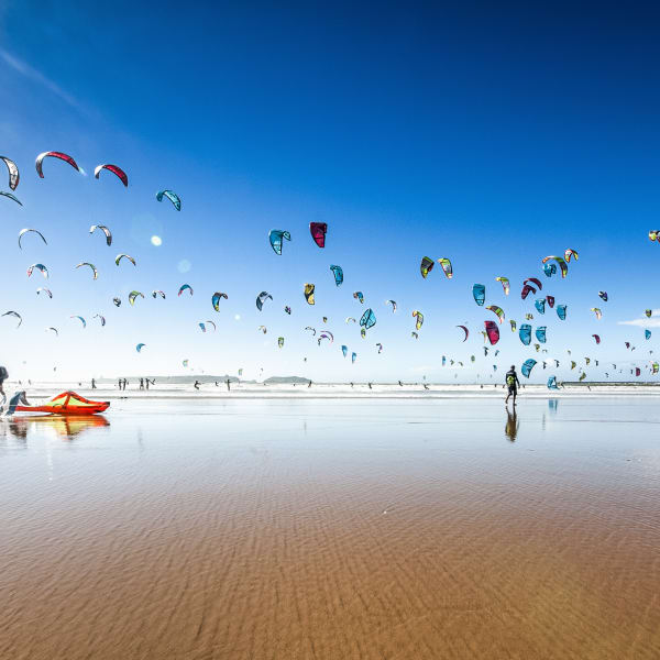 Riesige Menge von Kite- und Windsurfern an einem flachen Sandstrand in Marokko © iStock.com/Szymon Barylski