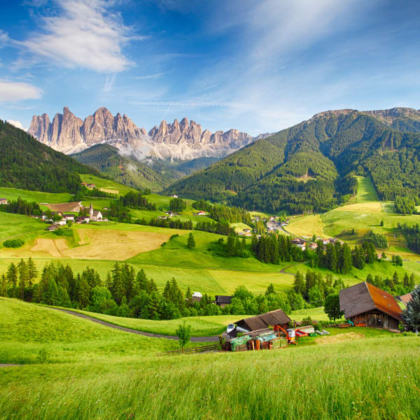 SchönesmBergpanorama mit den Dolomiten im Hintergrund und Hütten in grünem Tal © iStock.com/TomasSereda