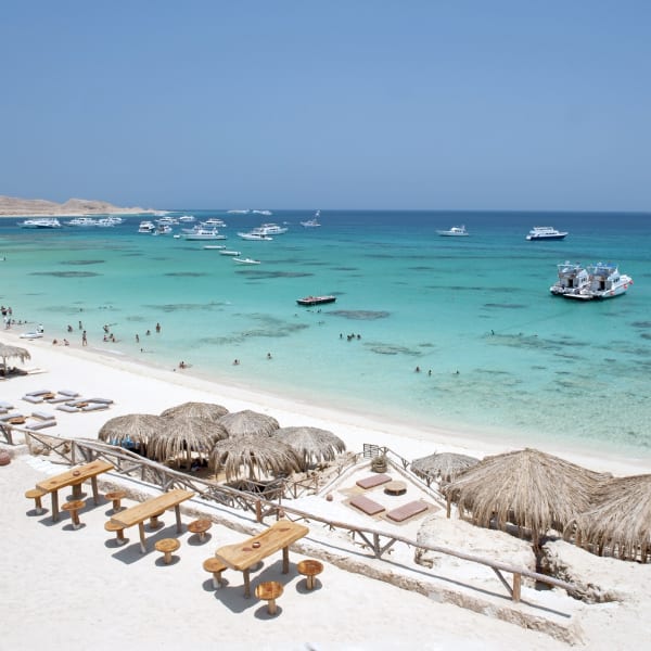Strand mit Schirmen in Ägypten mit Booten im Meer © iStock.com/majaiva