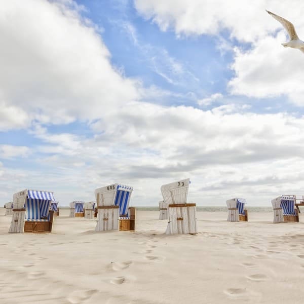 Strand mit blau weiß gestreiften Strandkörben auf Sylt © iStock.com/eyewave