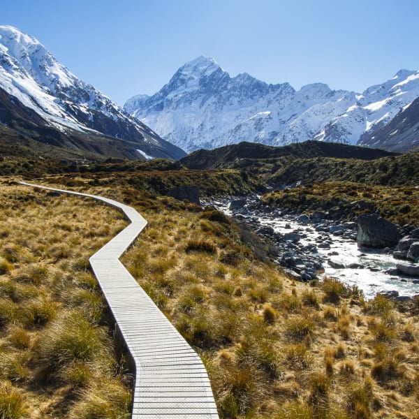 Ein Bergwanderweg in einem Tal von schneebedeckten Bergen umgeben in Neuseeland.