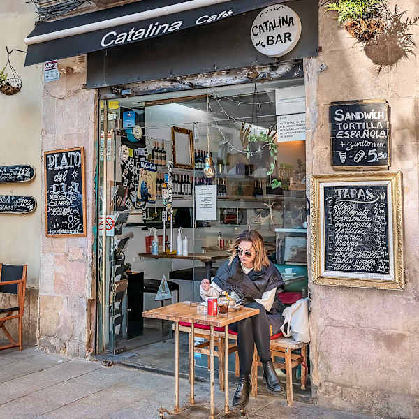 Eine Frau sitzt vor einem Café in Barcelona.