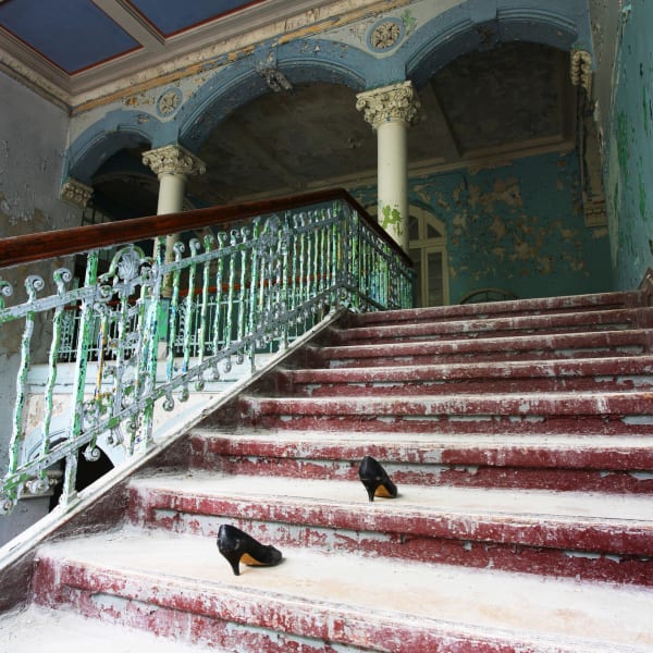 Ein Paar Frauenschuhe auf der Treppe eines heruntergekommenen Hauses.