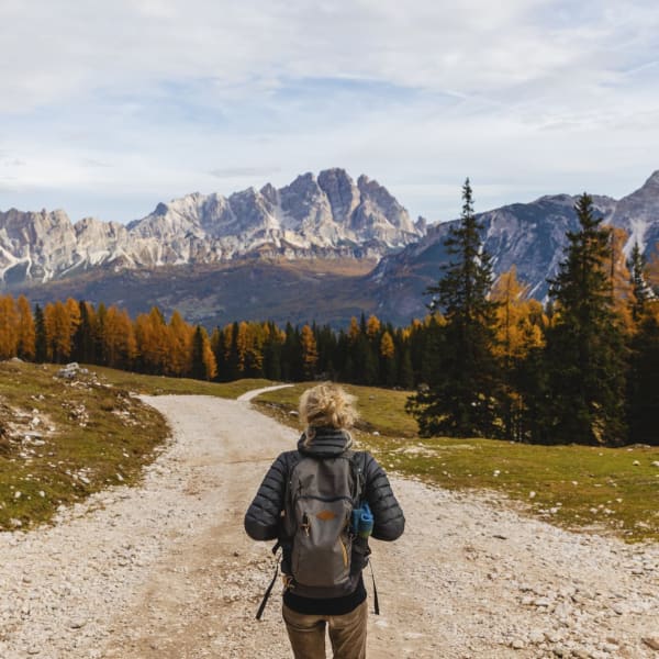 Eine junge Frau wandert auf einem Weg vor den Dolomiten in Italien.