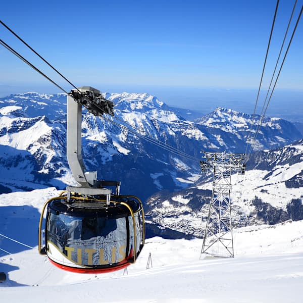 Eine moderne Gondel schwebt über einer verschneiten Berglandschaft.