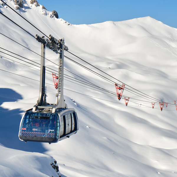 Eine Gondel schwebt über einem verschneiten Berghang.
