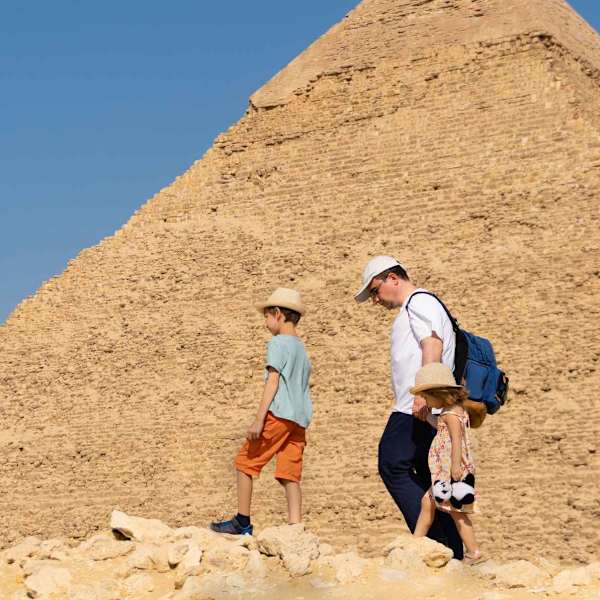 Ein Vater läuft mit seinen Kindern an einer Pyramide von Gizeh, Ägypten, entlang.