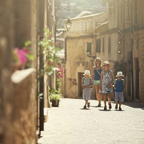 Mutter spaziert mit Kindern durch die Altstadt von Valdemossa auf Mallorca, Spanien