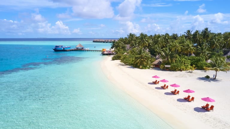 BlueOrange studio: Liegestühle und ein orangener Sonnenschirm an einem  schönen tropischen Strand auf den Malediven